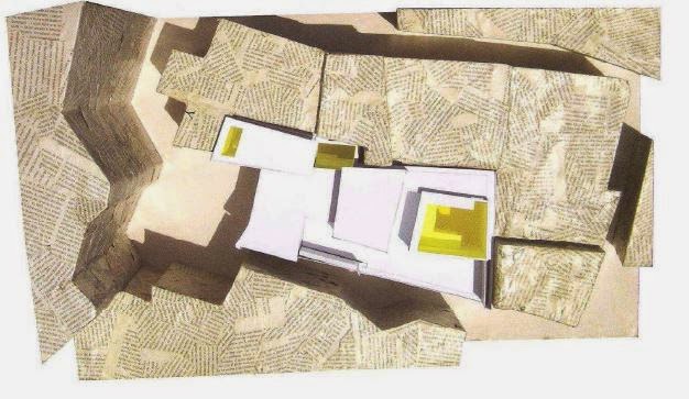Maqueta vista desde arriba con volúmenes blancos dentro de un tejido urbano de piedra.