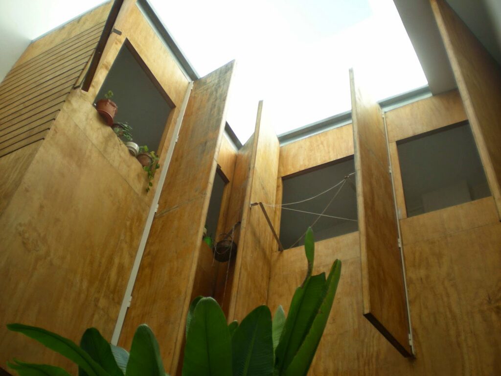 Vista desde abajo de fachadas y ventanas que delimitan un patio interior.