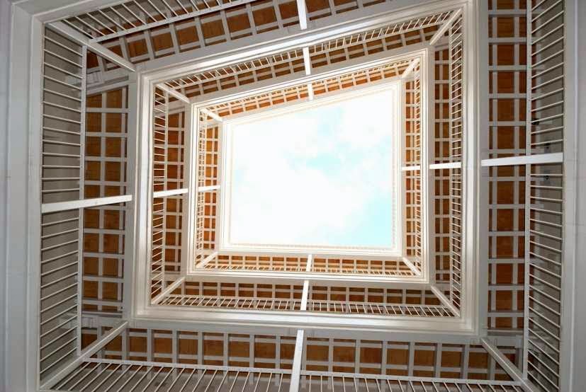 Vista vertical hacia el cielo desde un patio interior con galerías.