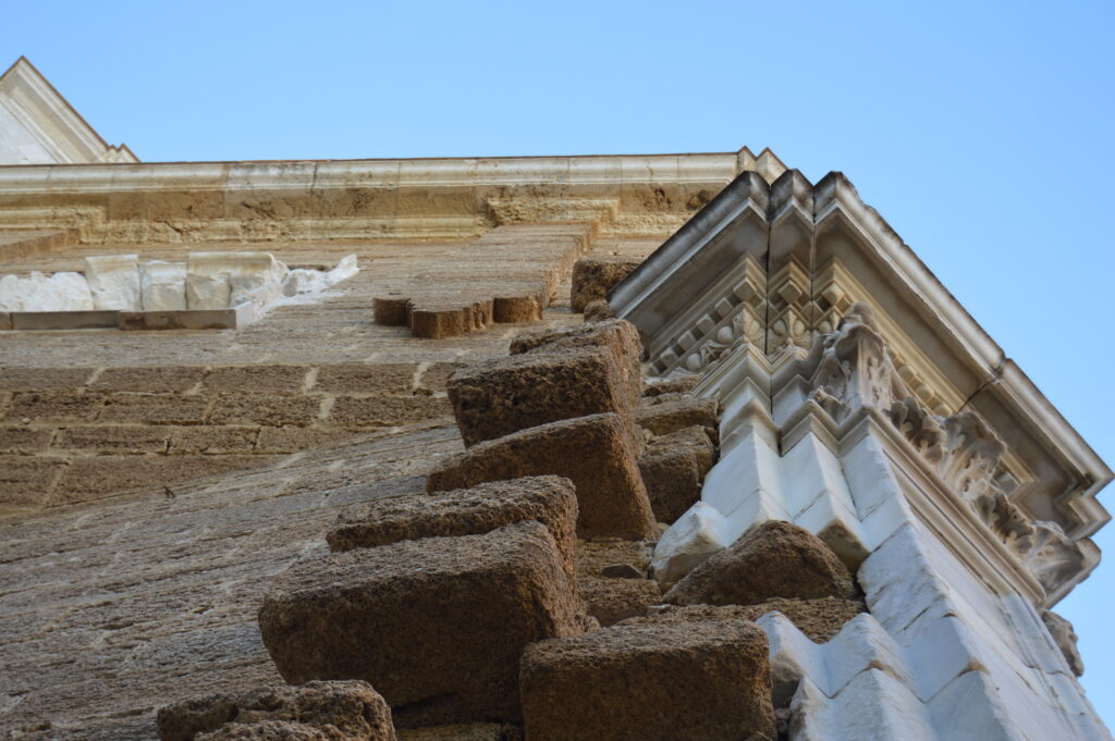 Detalle de columnas y cornisa de un edificio histórico visto desde abajo.