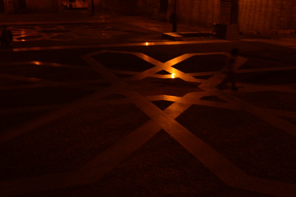 Sombras y franjas de luz sobre un pavimento oscuro.