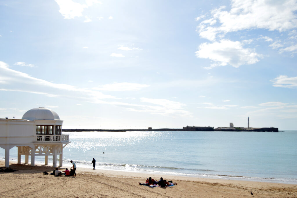 Playa y paseo junto al mar con una construcción aislada.
