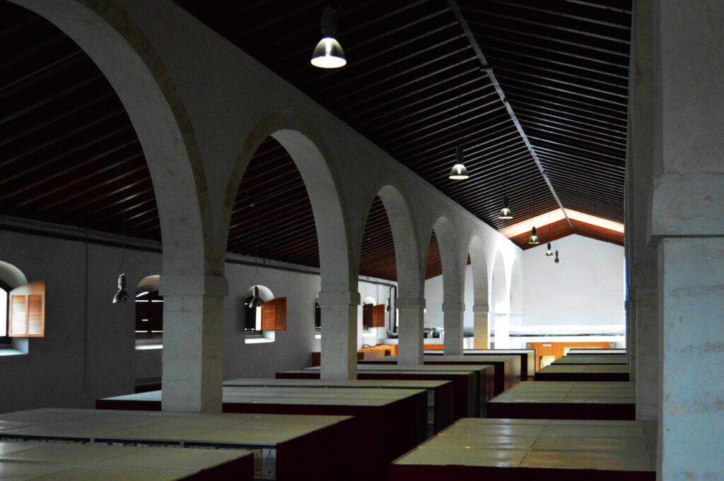 Sala interior con pilares, arcos y cubierta de madera.