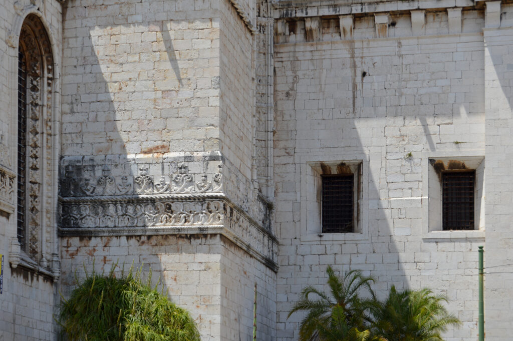 Detalle de muro de piedra y ventanas estrechas de un edificio histórico.