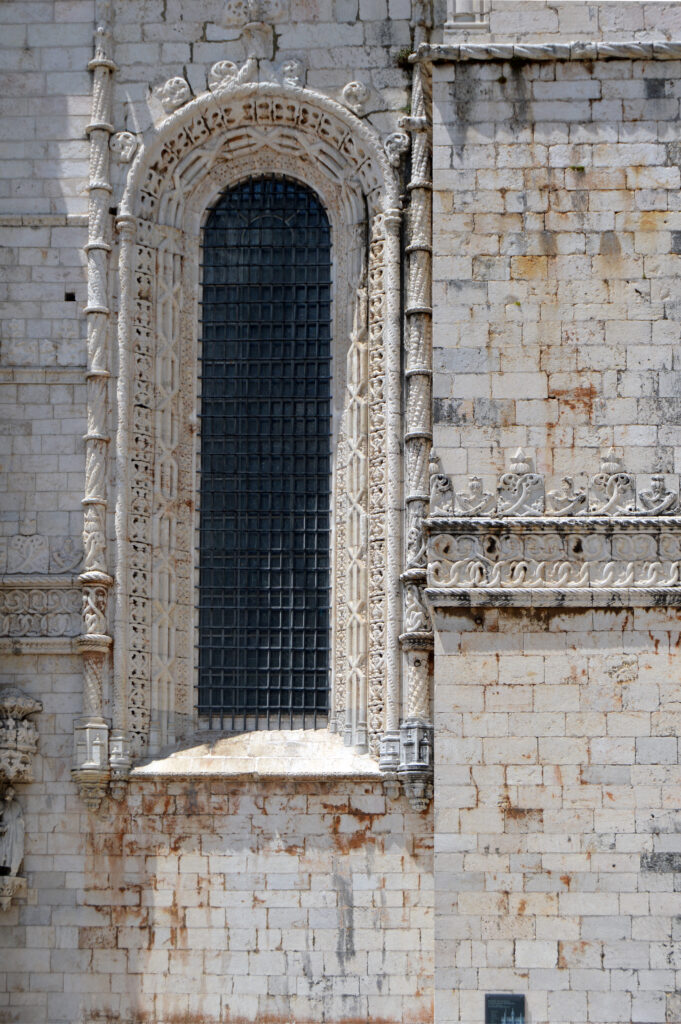 Ventana alta y estrecha abierta en un muro de piedra.