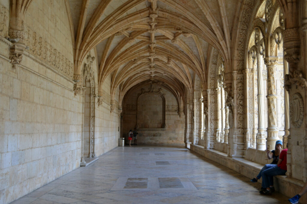 Galería interior abovedada con columnas y luz entrando por las ventanas.