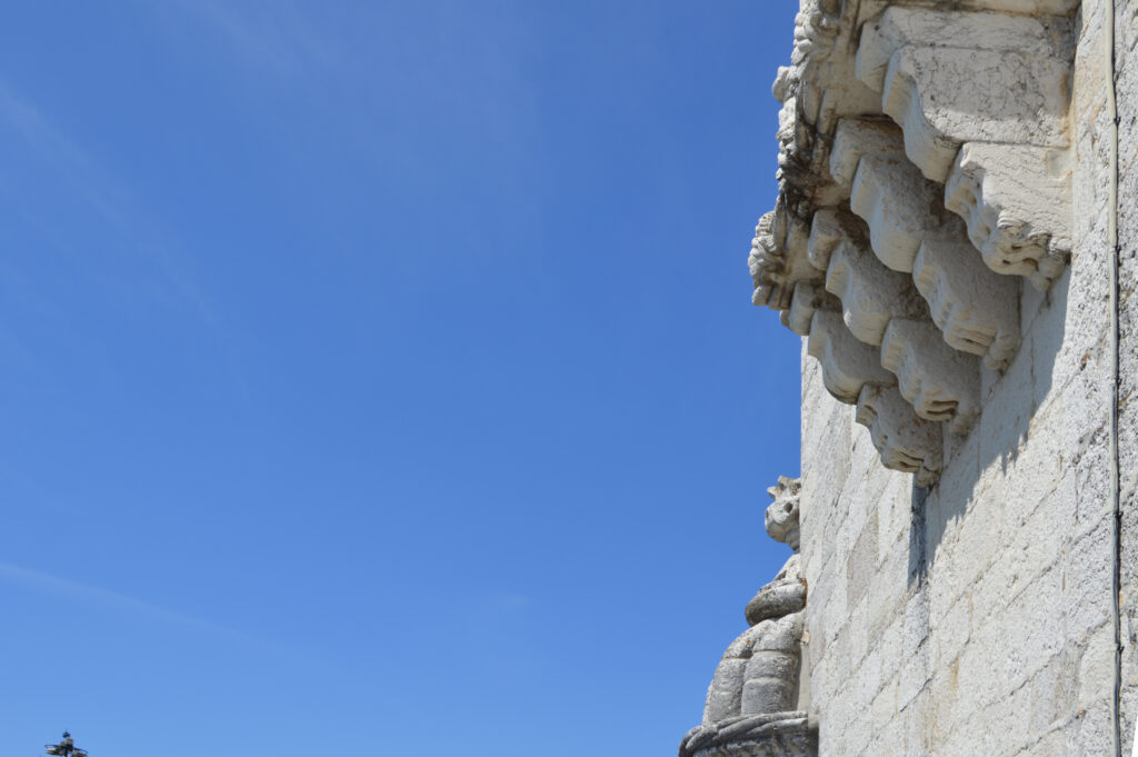 Detalle de piedra tallada en una fachada contra el cielo azul.