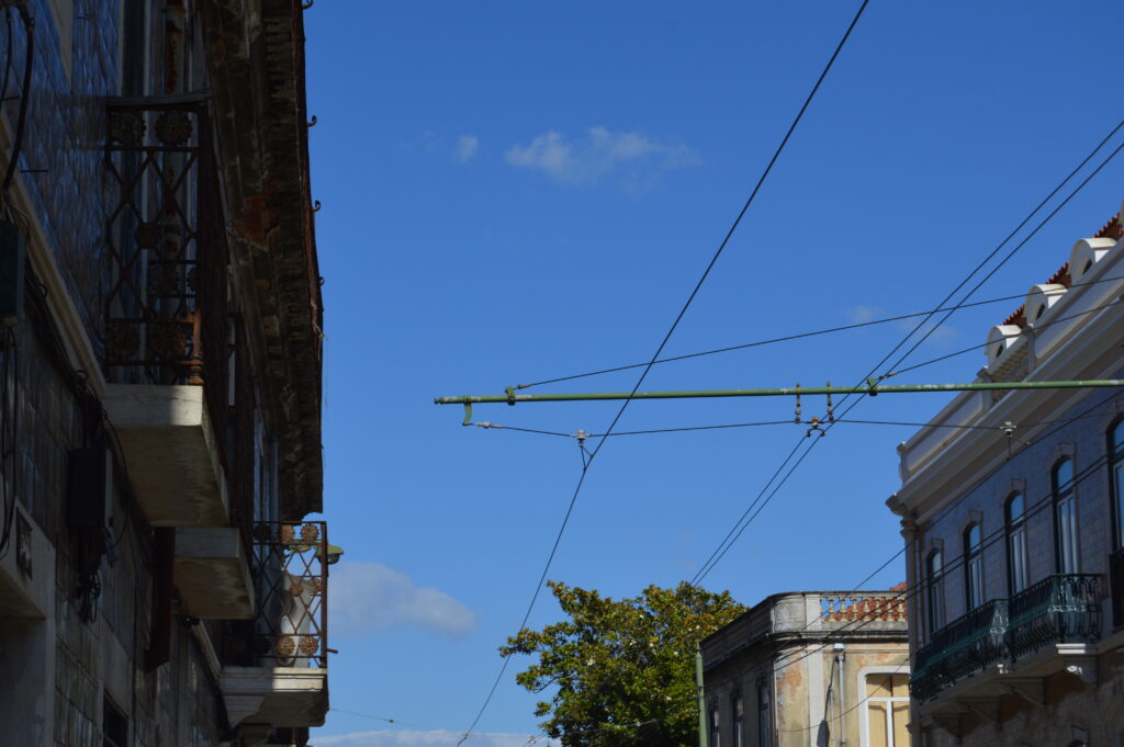 Calle urbana con cables de tranvía entre edificios.