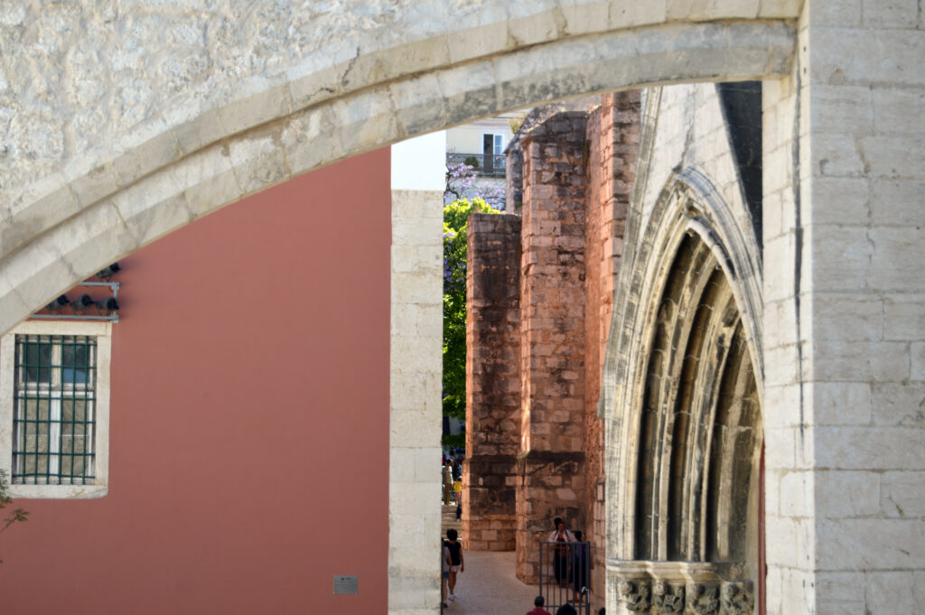 Arco de piedra junto a una fachada rosa.