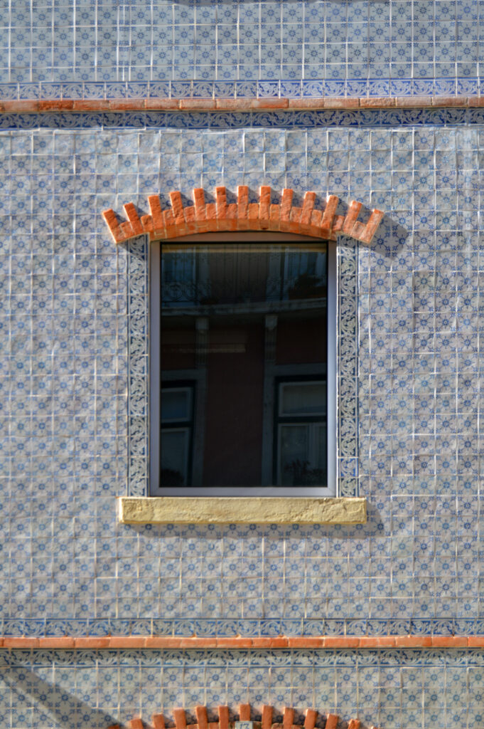 Ventana con moldura amarilla en fachada revestida de azulejos.